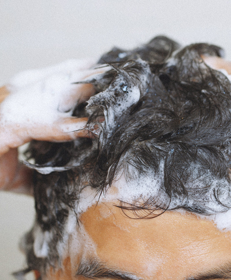 Mann massiert schäumendes Shampoo intensiv in die Kopfhaut ein – Haarpflege-Routine für gesunde Kopfhaut.